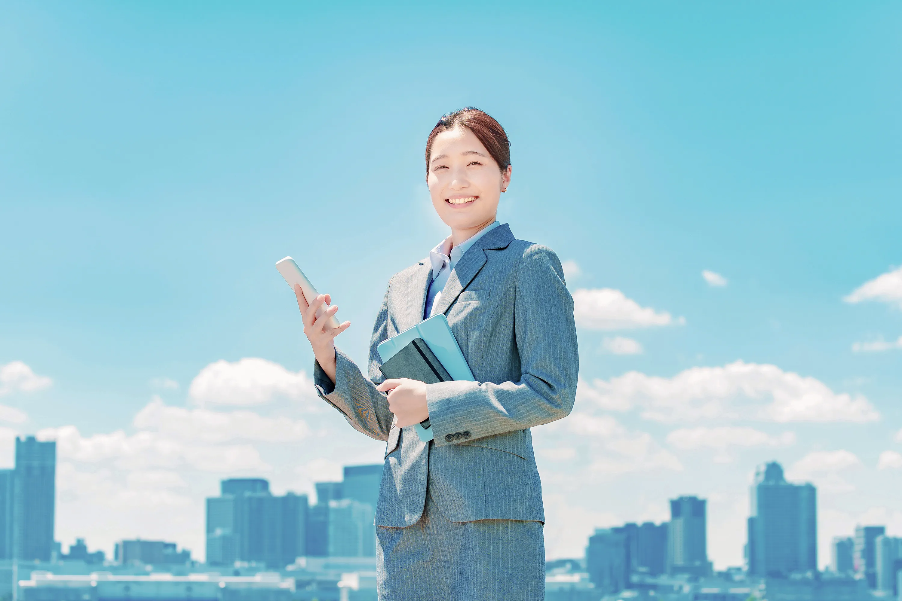 スマートフォンを持って笑顔で立つ女性